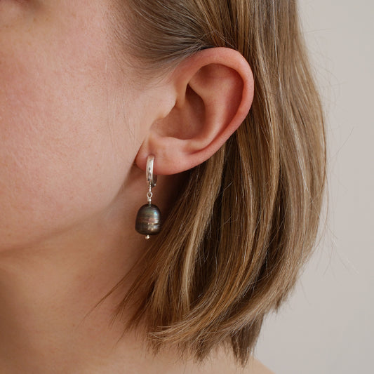 srebrny kolczyk z szarą perła na uchu